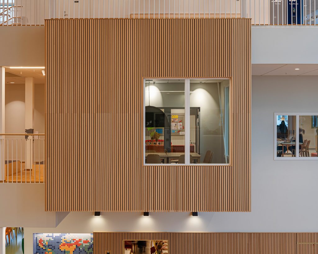 Hanging cube clad with acoustic timber panels in school