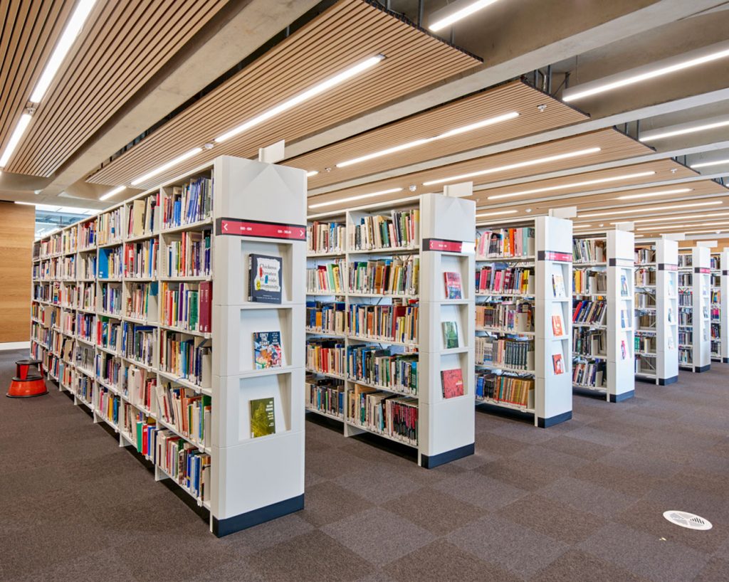Bokhyllor i bibliotek med akustikpaneler av trä ovanför