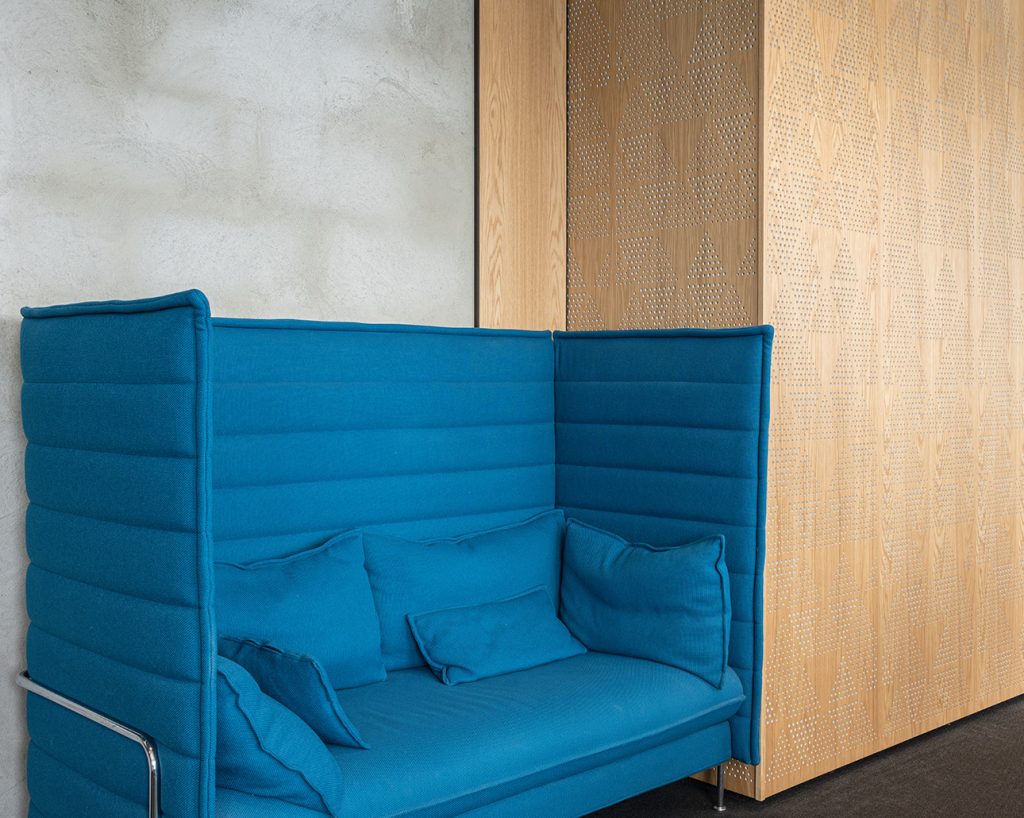 Blå soffa med perforerade paneler bakom